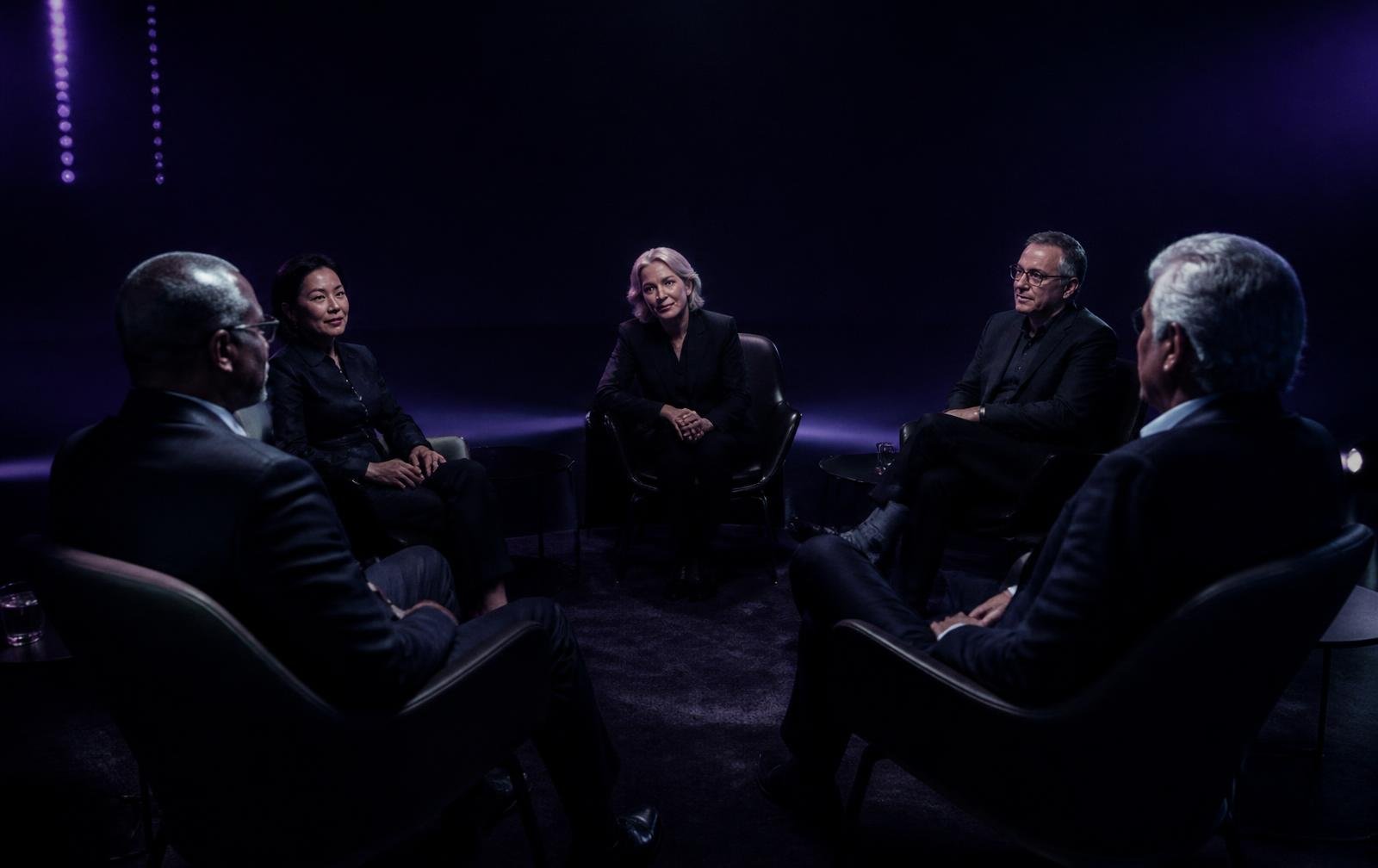 Senior leaders in conversation inside a dark executive learning studio